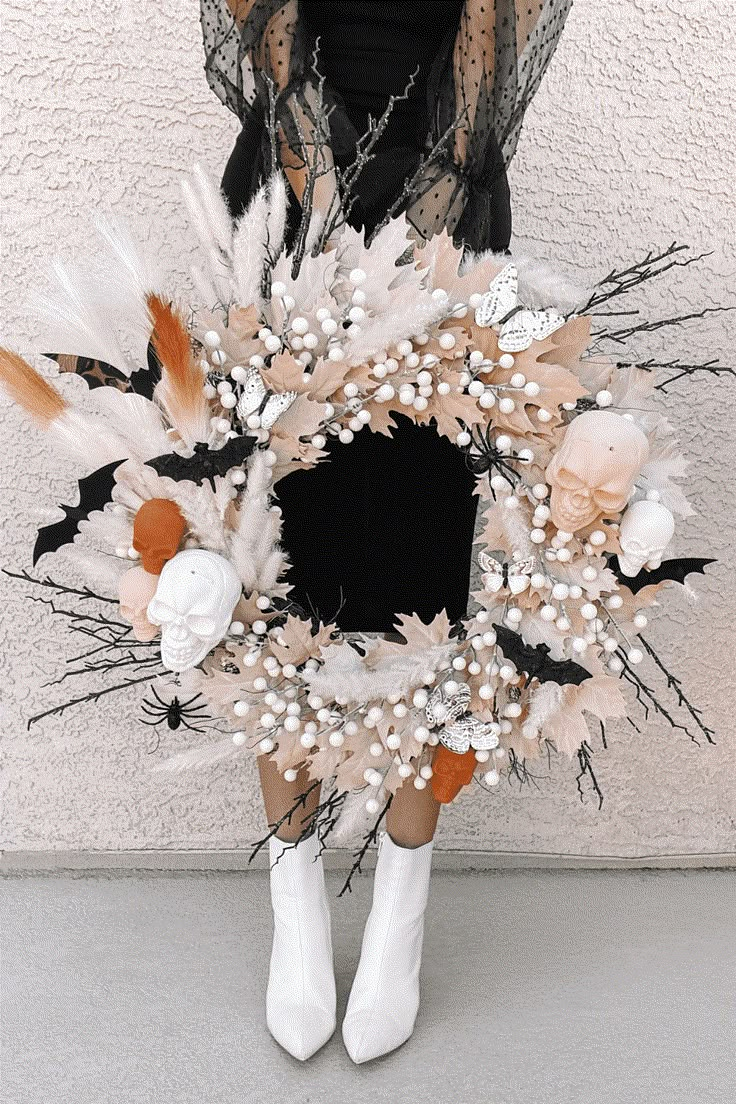 a woman is holding a wreath with feathers and flowers on it, in front of a white wall