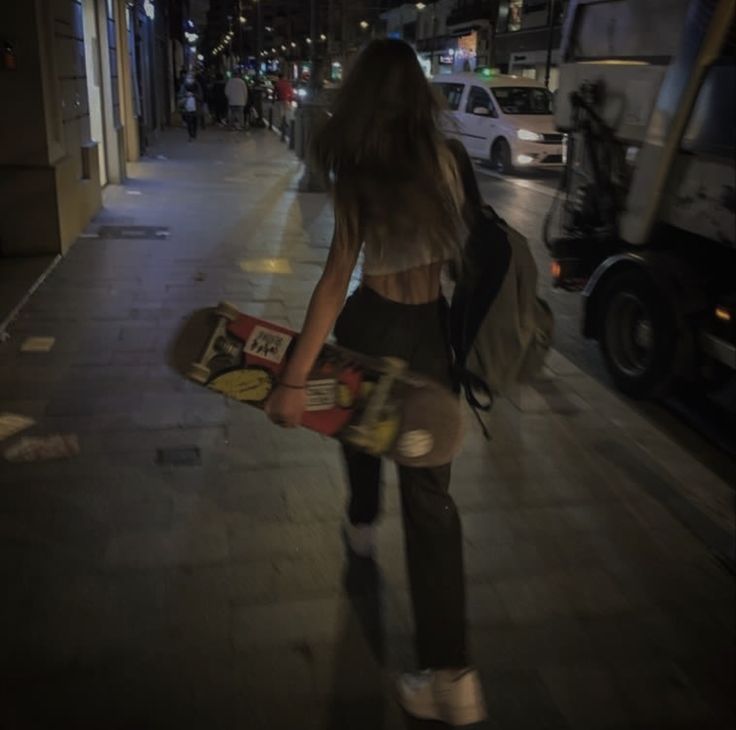 a woman is walking down the street with her skateboard