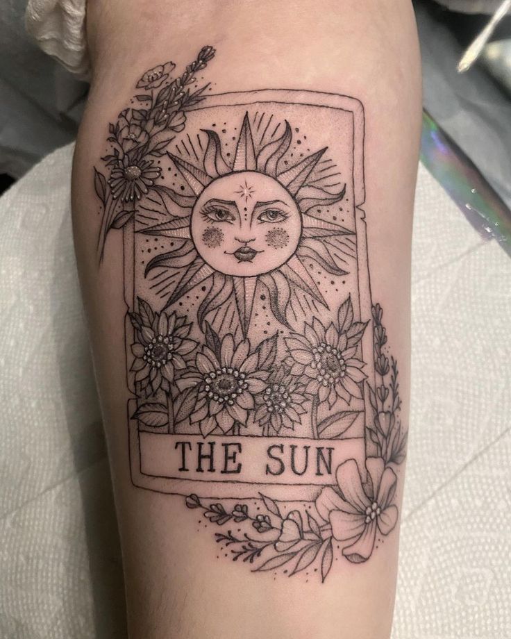 a sun tattoo on the leg with flowers around it and an inscription that reads, the sun