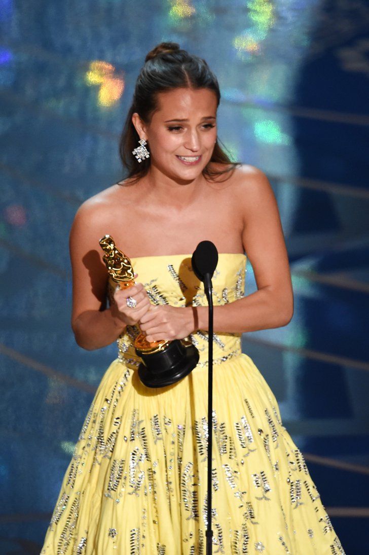 a woman in a yellow dress holding an award