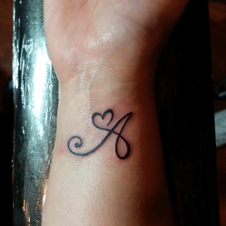 a small tattoo on the wrist of a woman's left hand with a heart