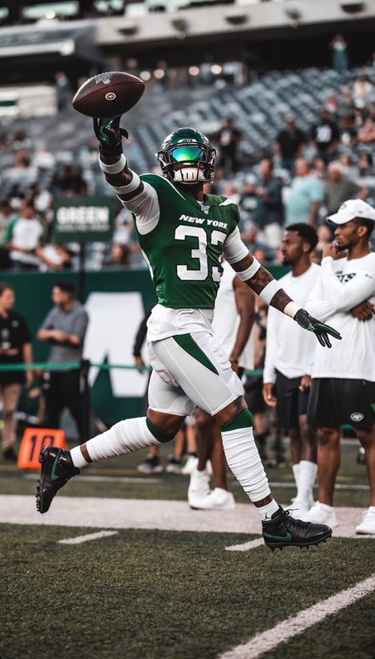 a football player catching a ball in the air with his arm out and people watching