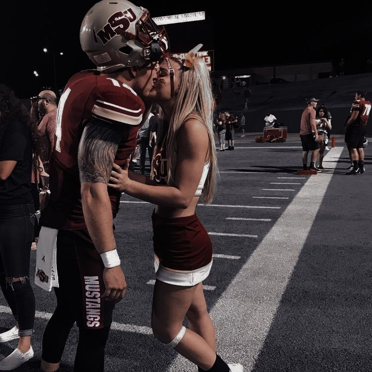 two football players standing next to each other in a parking lot with fans behind them