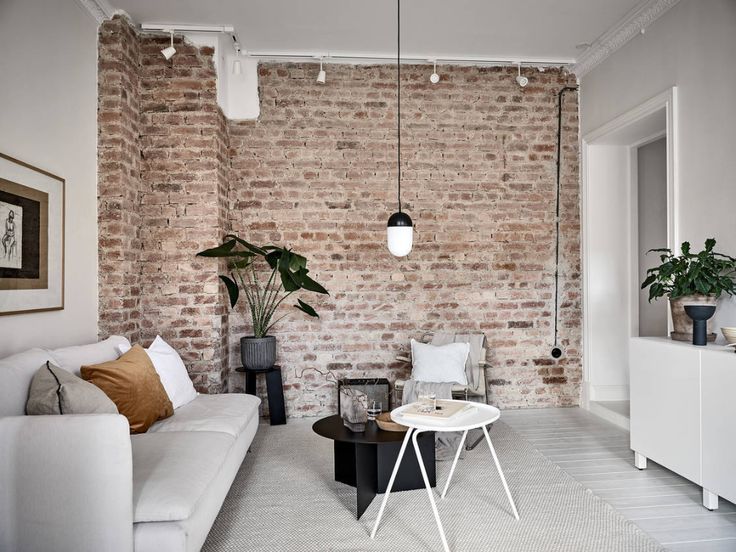 a living room filled with furniture and a brick wall behind the couch is a coffee table