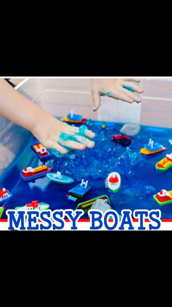 a child playing with messy boats in a plastic container on top of a blue table