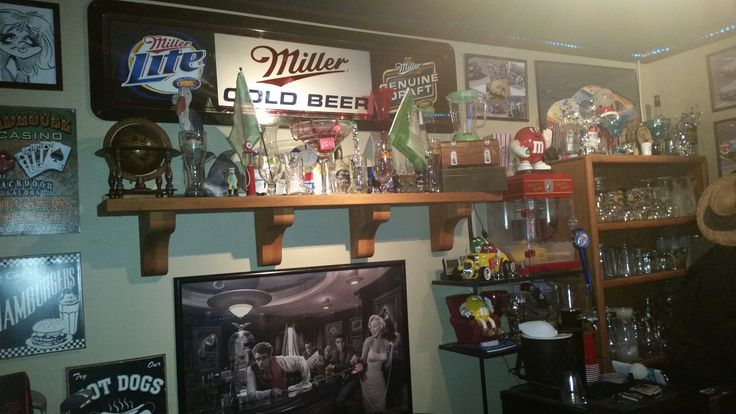 a man sitting in front of a shelf filled with liquor bottles and other alcohol items