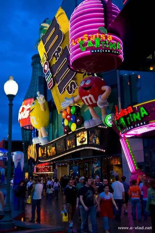 many people are walking on the street in front of neon signs and buildings at night