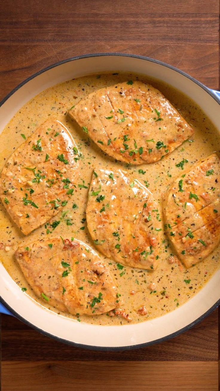 some chicken is cooking in a pan with gravy on the side and garnished with parsley