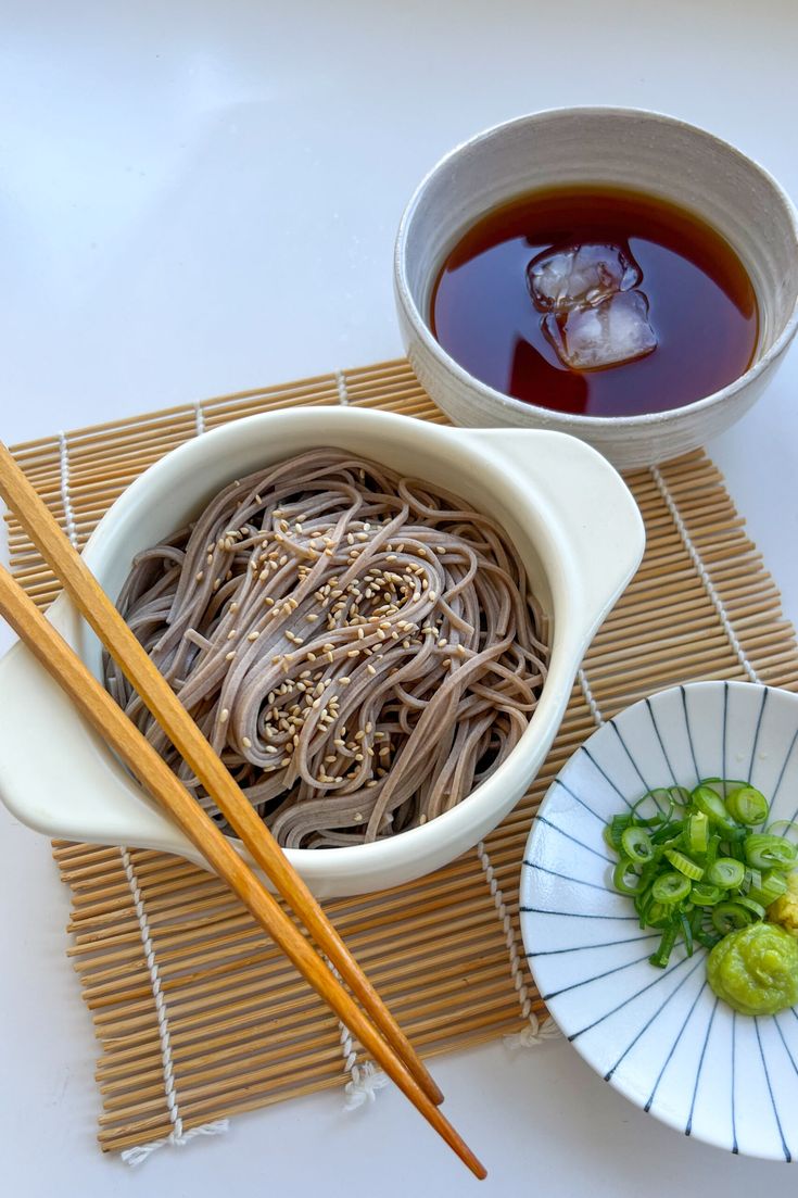 chopsticks and bowls of noodles on a mat