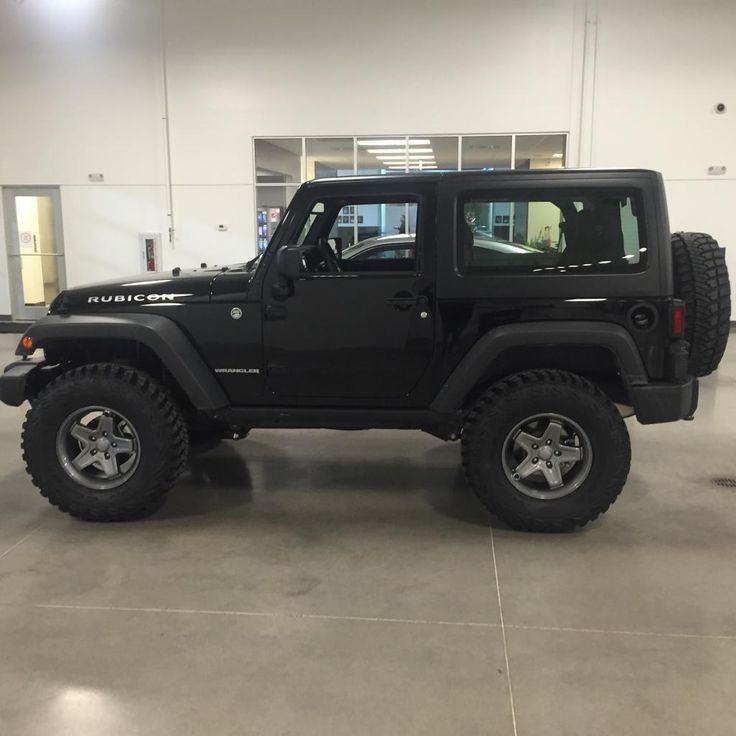 a black jeep is parked in a large room with white walls and flooring on the other side