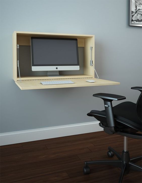 a computer desk with a monitor, keyboard and chair in front of it on the wall