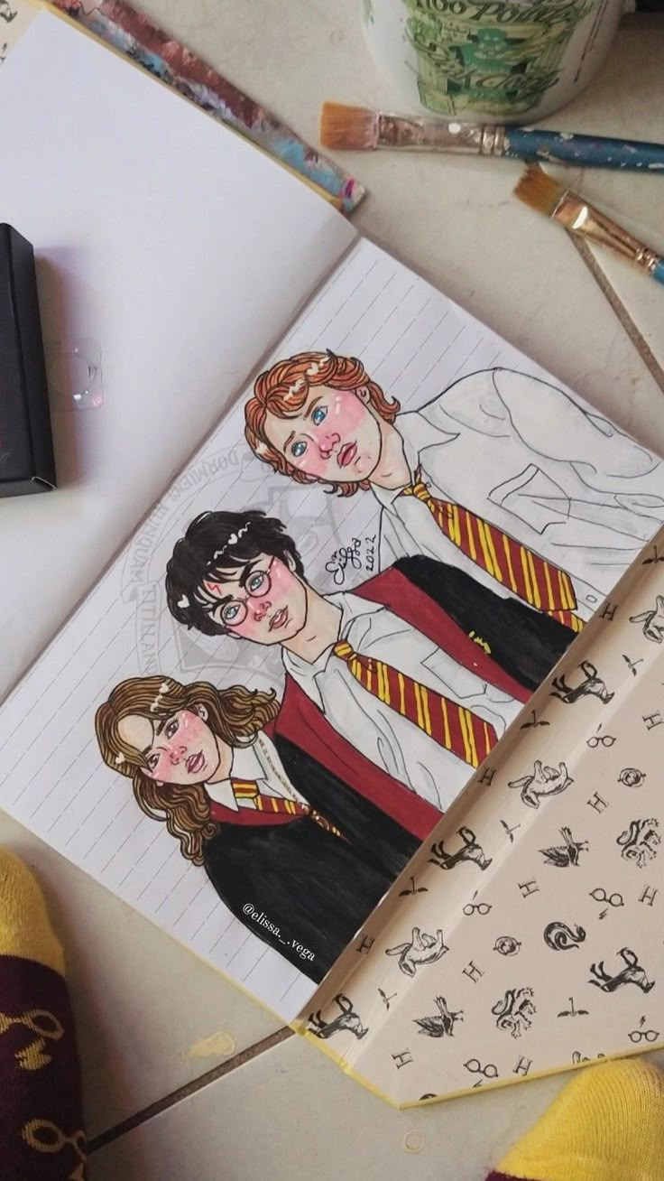 an open harry potter notebook with two children's drawings on it