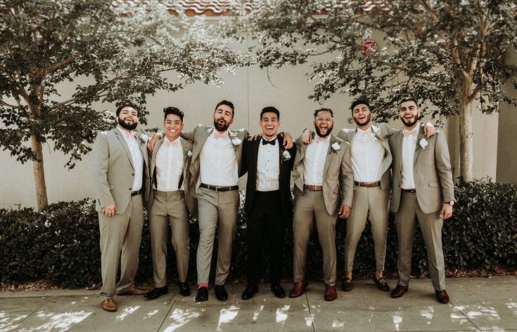 a group of men standing next to each other in front of a building with trees