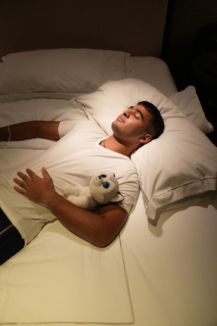 a man laying in bed holding a stuffed animal