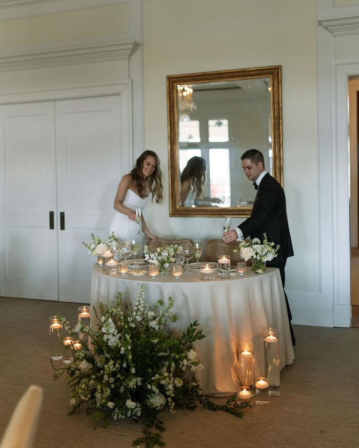 a bride and groom cutting their wedding cake at the reception table with candles in front of them