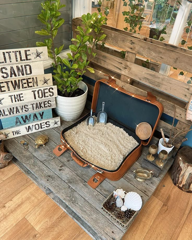 an open suitcase sitting on top of a wooden table next to plants and other items