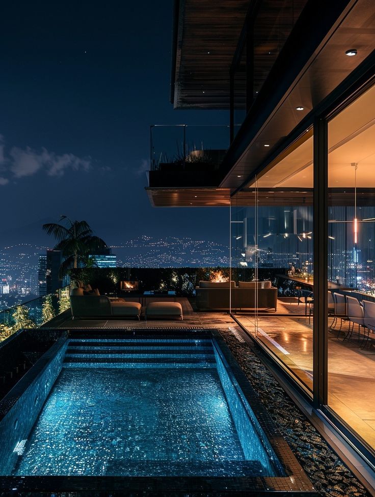 an indoor swimming pool in the middle of a night time scene with city lights behind it