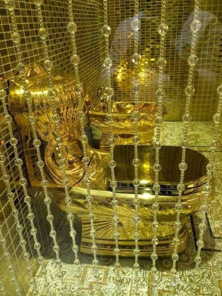 a gold toilet in the middle of a room with beads on the walls and around it