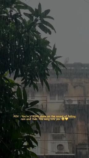 the rain is falling down on an apartment building and there are trees in front of it