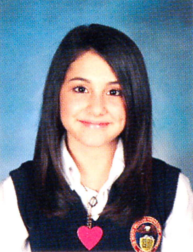 a young woman wearing a school uniform and smiling at the camera with a heart on her chest