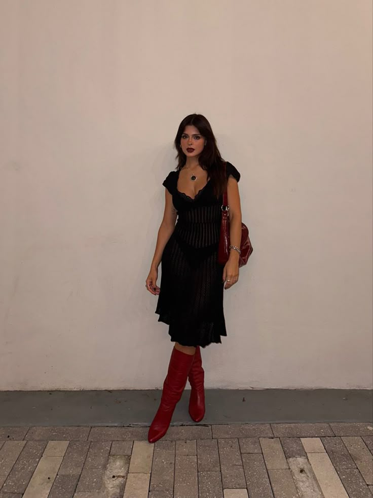 Red boots styled with a black crochet dress and red slouchy bag Red Calf Boots Outfit, Winter Heels Outfit Dress, Black Mini Skirt Black Boots, Crochet Dress With Boots, Fall Skirt And Dress Outfits, Red Boots Aesthetic Outfit, Black Dress Red Cowgirl Boots, Black Dress Red Boots Outfit, Black Skirt And Black Boots Outfit