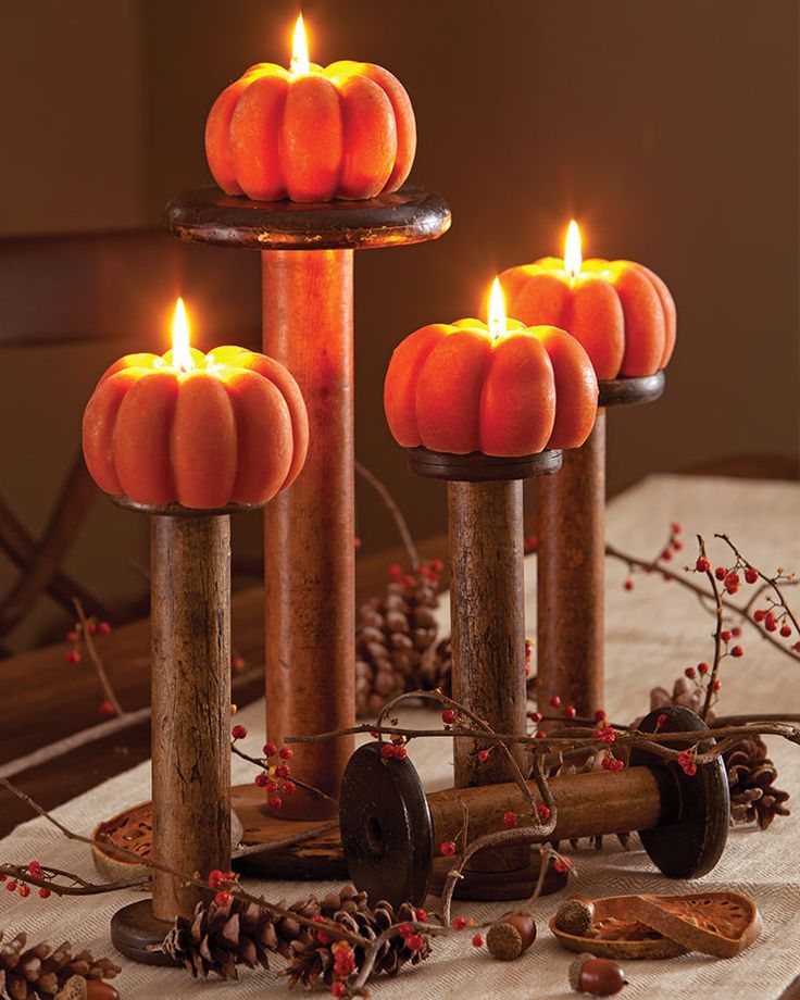 four candles are lit in the shape of pumpkins