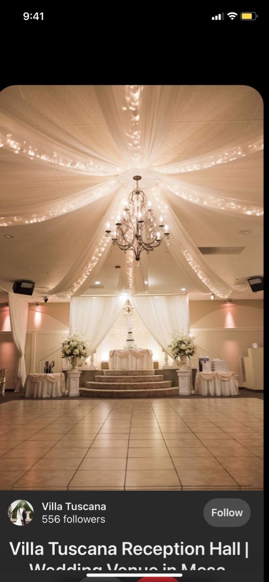 the inside of a wedding reception with chandelier and white drapes on the ceiling