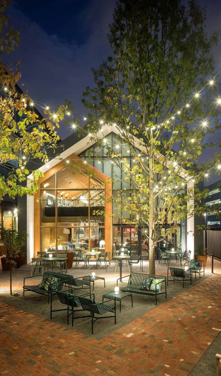 an outdoor seating area is lit up at night with string lights strung from the trees