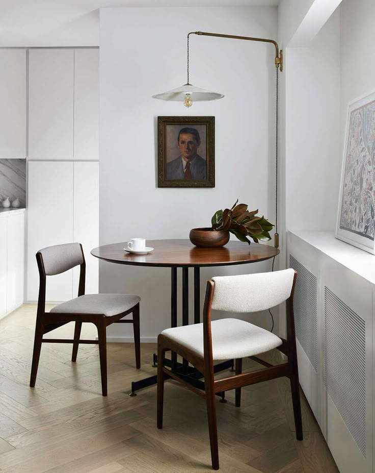 a dining room table with two chairs and a painting hanging on the wall above it