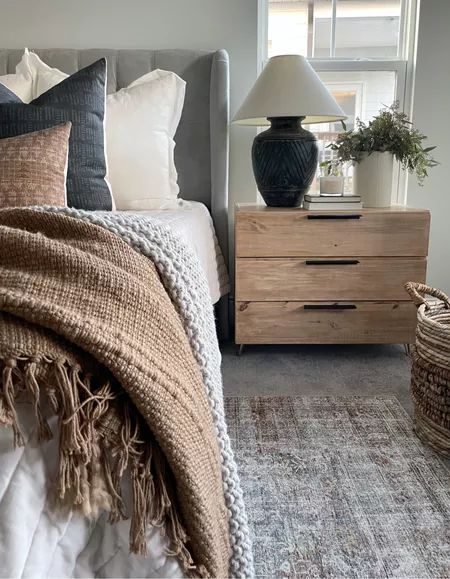 a bed sitting next to a window in a room with pillows and blankets on top of it