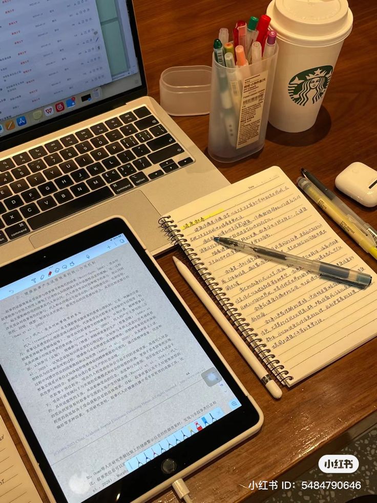 an open laptop computer sitting on top of a wooden desk next to a cup of coffee