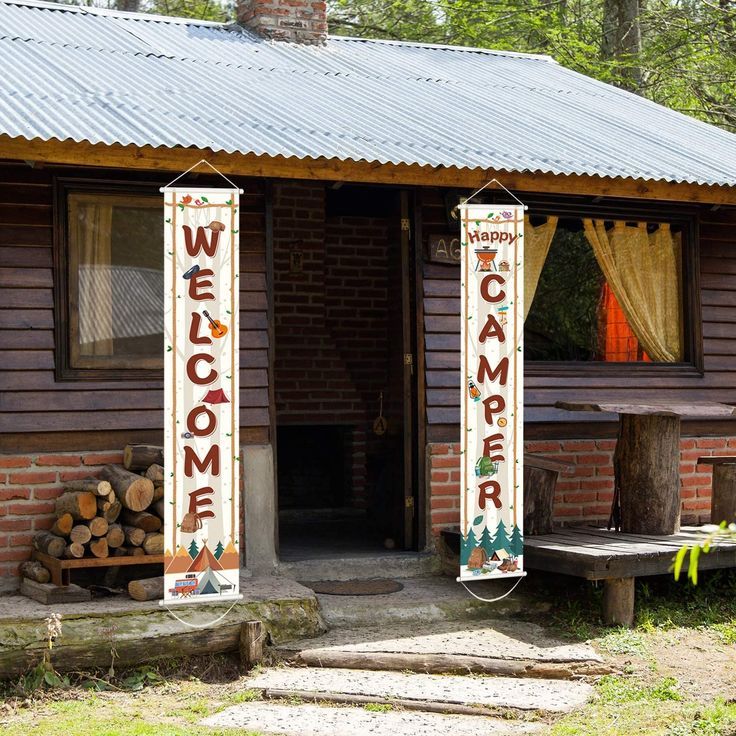 a small cabin with two welcome signs on the front door and one sign that says welcome to camper