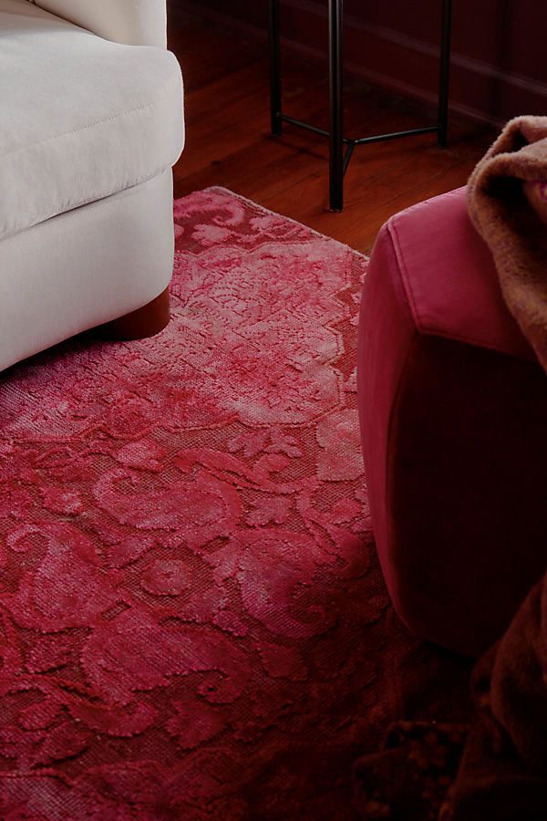 a living room with a white couch and red rug on the floor next to a chair