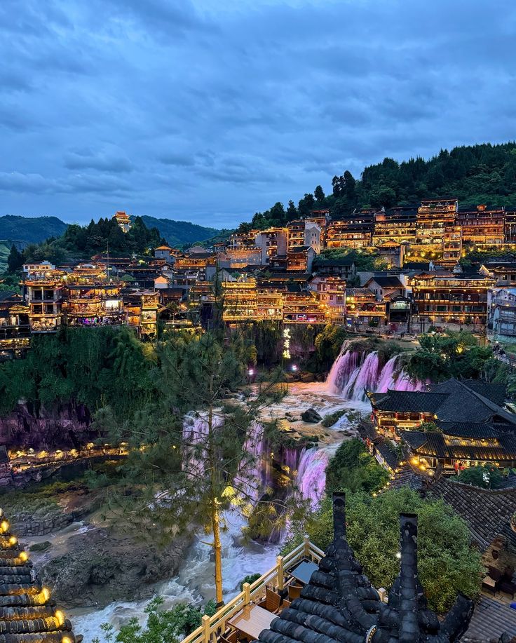 the city is lit up at night with colorful lights on it's buildings and trees