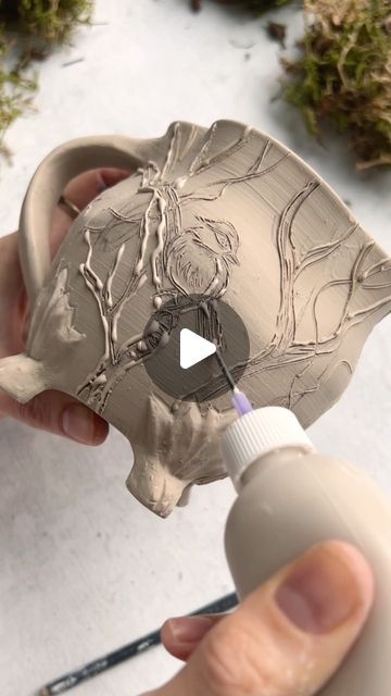 a person is painting a vase with white paint