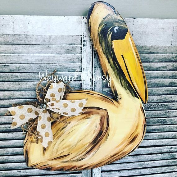 a painted pelican sitting on top of a door with a bow around it's neck