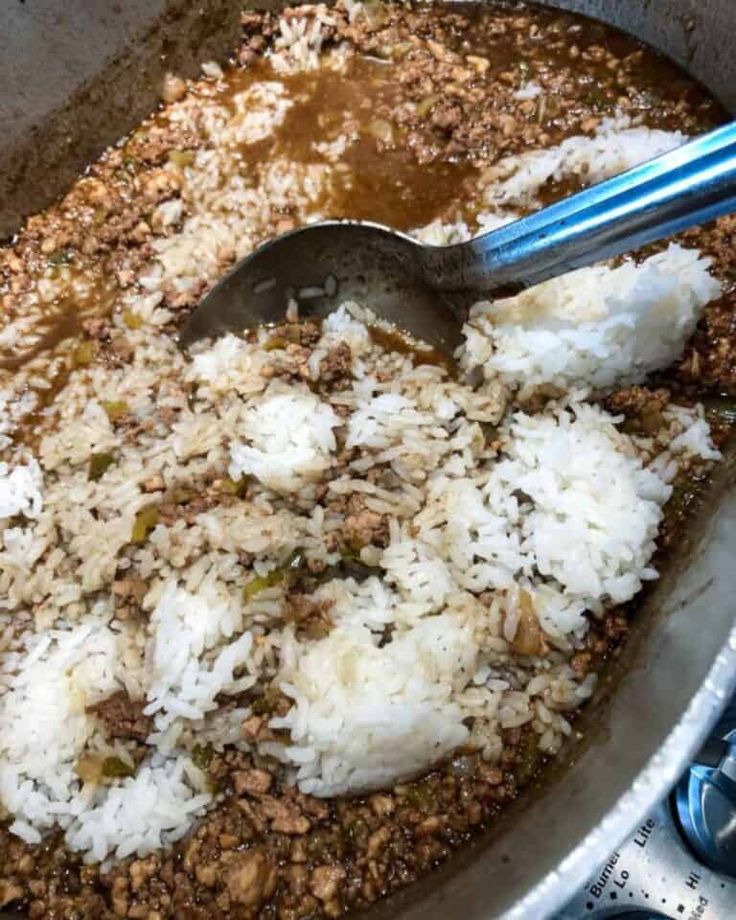 rice is being cooked in a pan with spoons