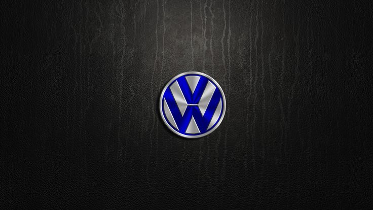 the volkswagen logo is shown on a dark wood background with light coming from behind it