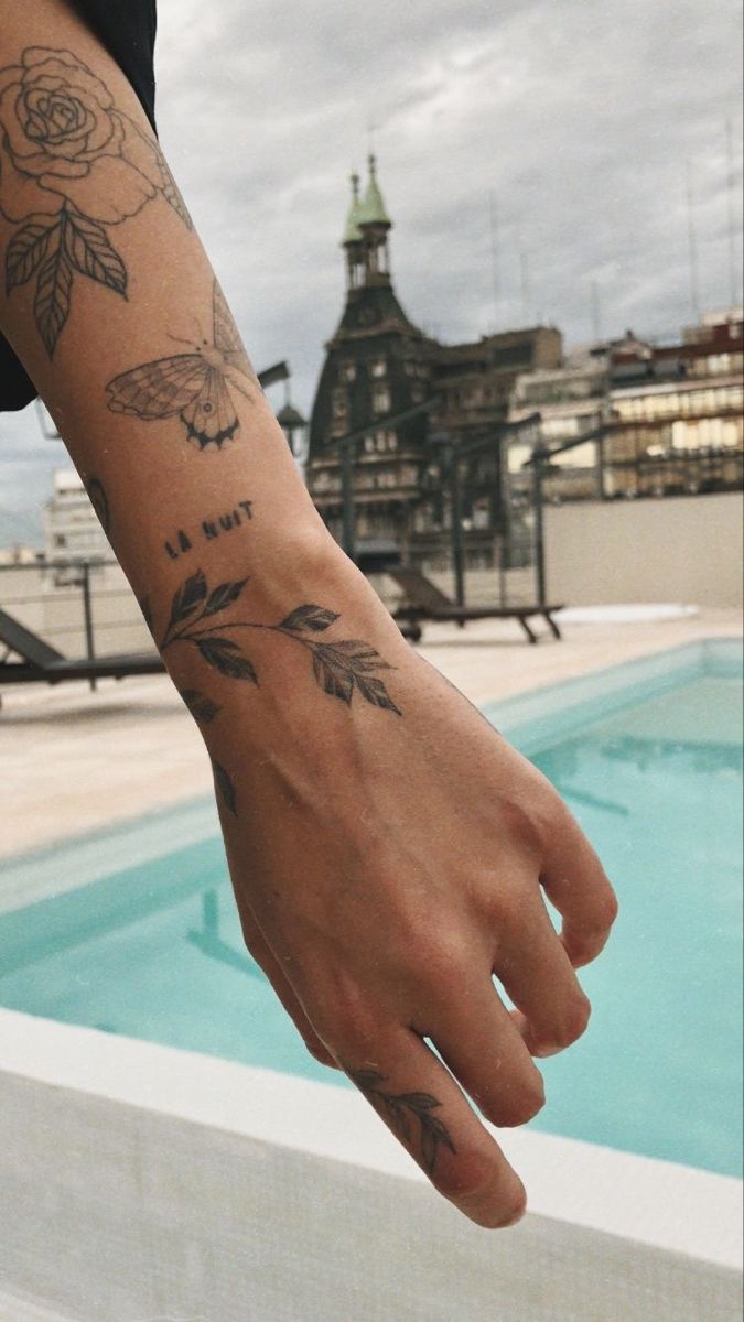 a person's arm with tattoos near a swimming pool