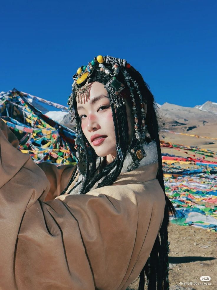 a woman with dreadlocks on her head in front of mountains and prayer flags