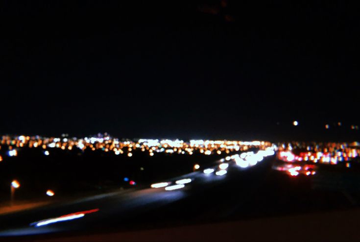 blurry image of city lights at night taken from the top of an airplane window