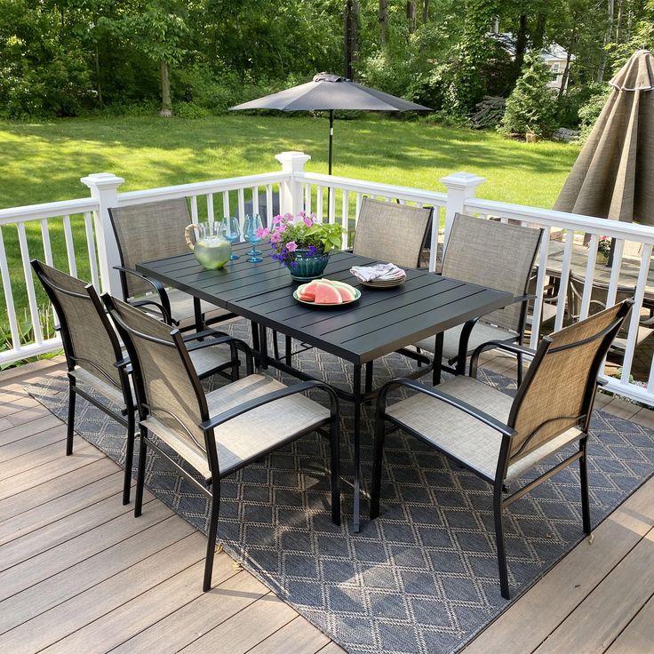 a table and chairs on a deck with an umbrella in the backgroung