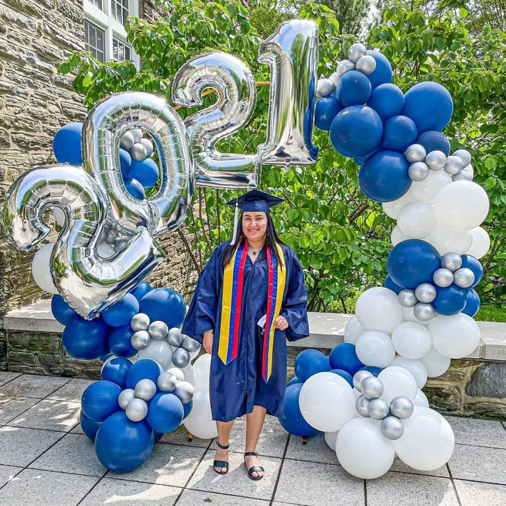 a woman in graduation gown standing next to balloons and letters that spell the number twenty five