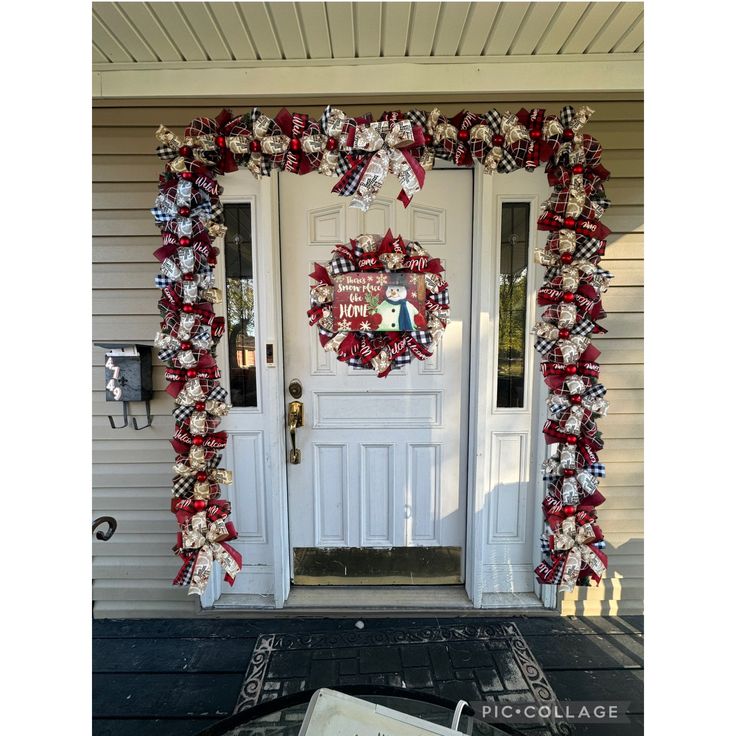 a christmas wreath on the front door of a house decorated with red, white and blue ribbon