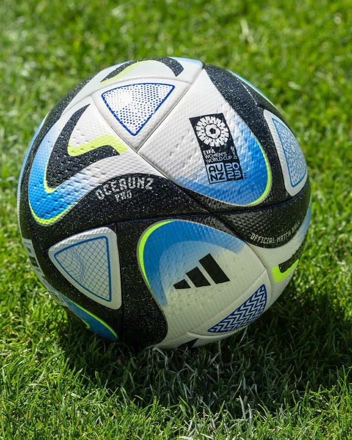 a soccer ball sitting on top of a green grass covered field with white and blue markings