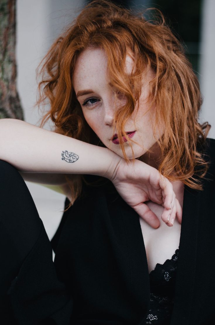 a woman with red hair and tattoos on her arm