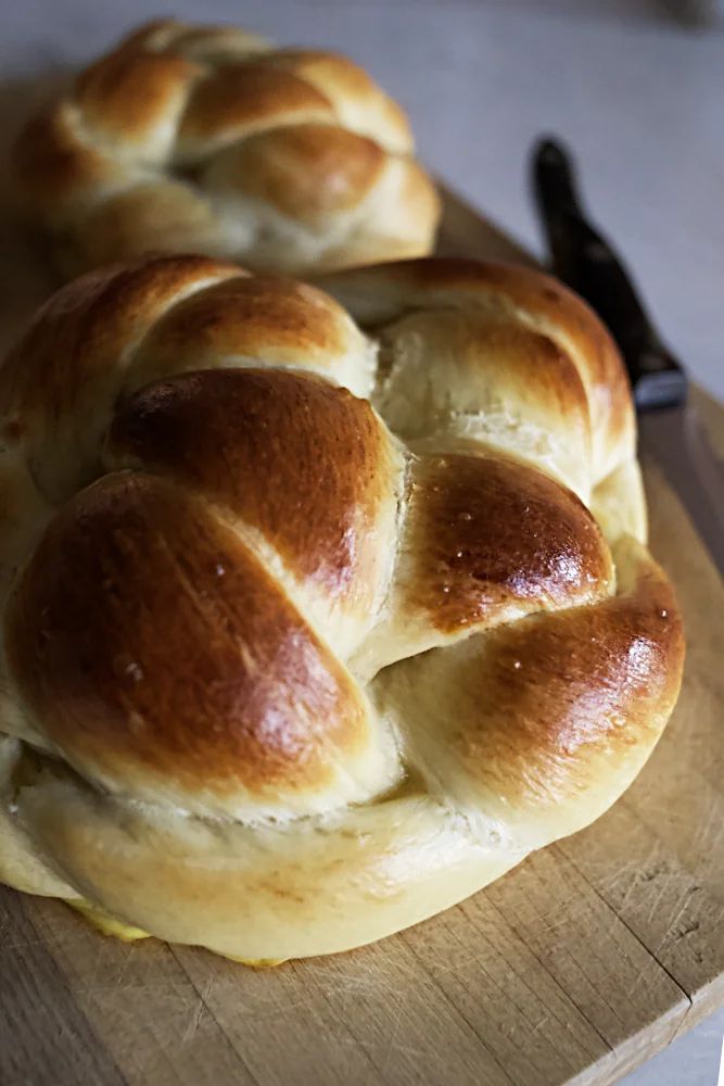 two hot cross buns sitting on top of a cutting board