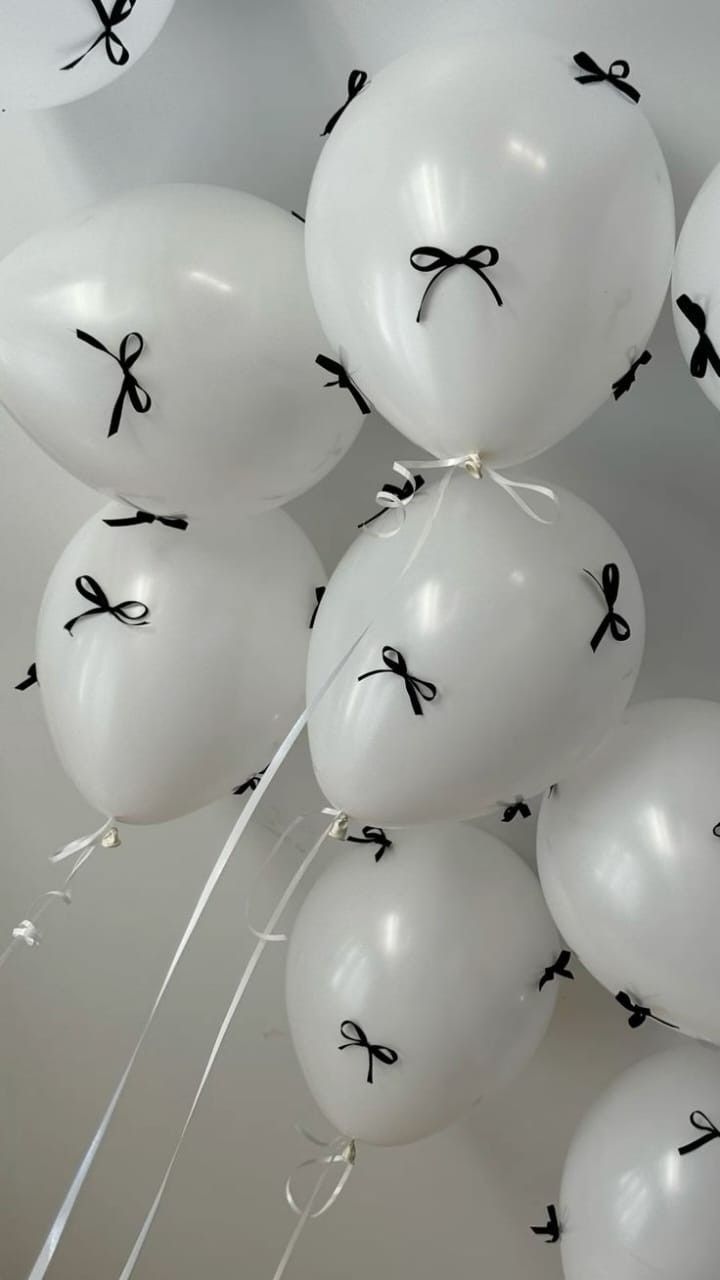 white balloons with black letters and bows tied to them