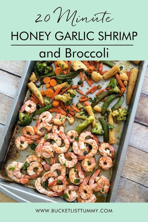 a pan filled with shrimp and broccoli on top of a wooden table next to a