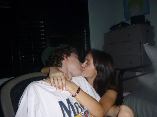 a man and woman kissing each other while sitting on a couch in a room at night